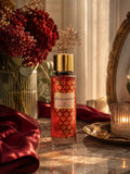 Flacon de brume parfumée Rouge Absolu 250 ml Gris Montaigne Paris sur un plateau de marbre, drapé de satin bordeaux et miroir doré