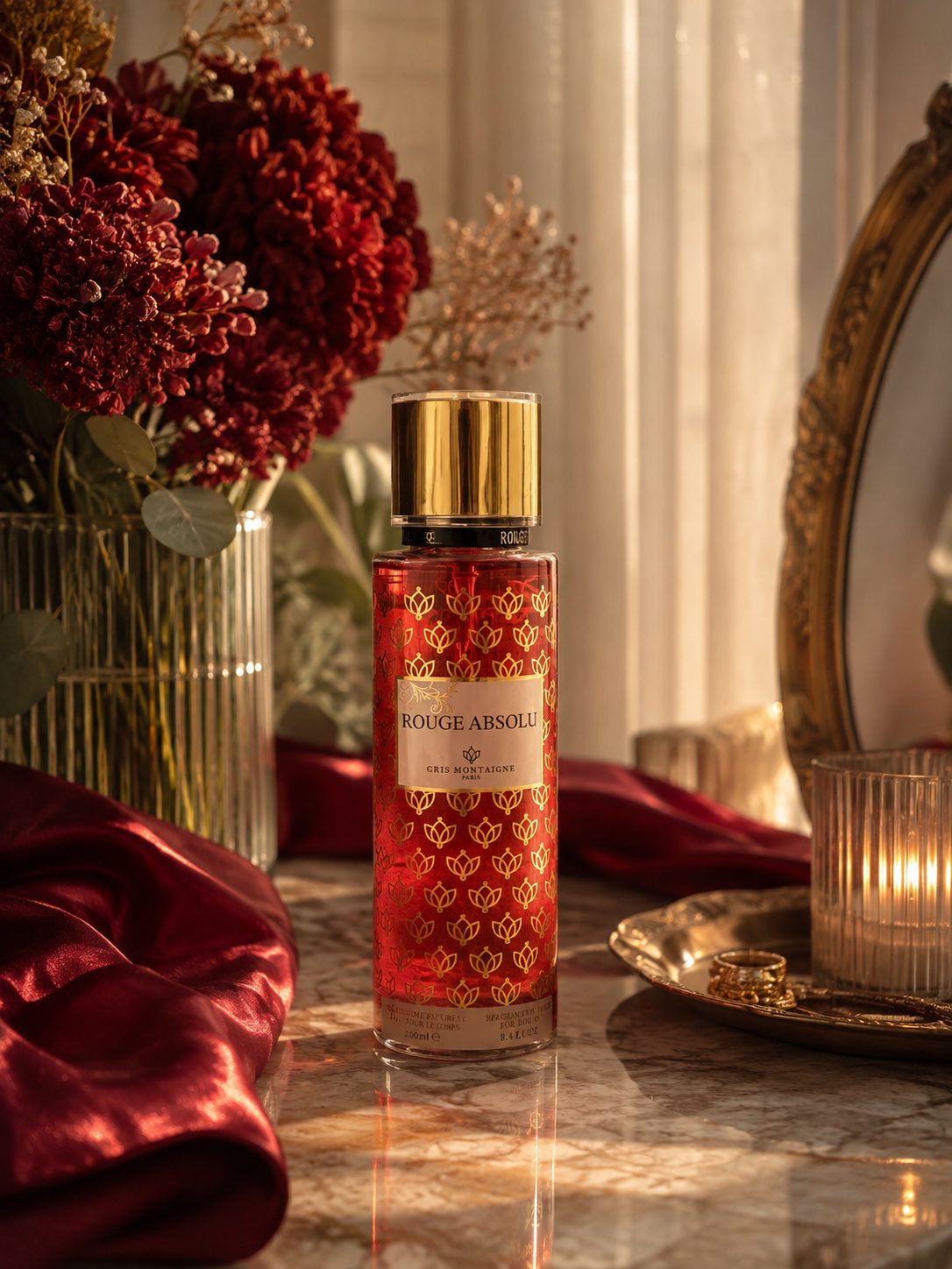 Flacon de brume parfumée Rouge Absolu 250 ml Gris Montaigne Paris sur un plateau de marbre, drapé de satin bordeaux et miroir doré