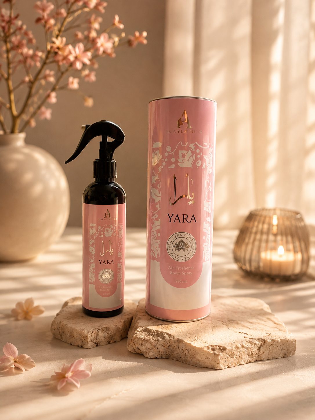 Parfum d'intérieur Yara 250 ml, vaporisateur et son tube rose posés sur travertin avec des fleurs de cerisier